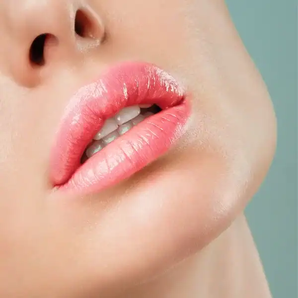 Lèvres d'une femme avec du rouge à lèvres rose sur fond bleu vif.