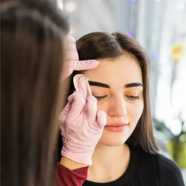 Une femme se fait épiler les sourcils par une professionnelle dans un salon de beauté.